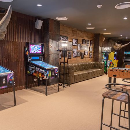 Grand Bavaro Princess All Suites Resort, Spa&Casino Esterno foto The photo shows a game room with a cozy and fun atmosphere. On the left side, there are two pinball machines with colorful graphics. A tufted green sofa is situated against the wall, providing a comfortable seating area. The walls are decorated with 