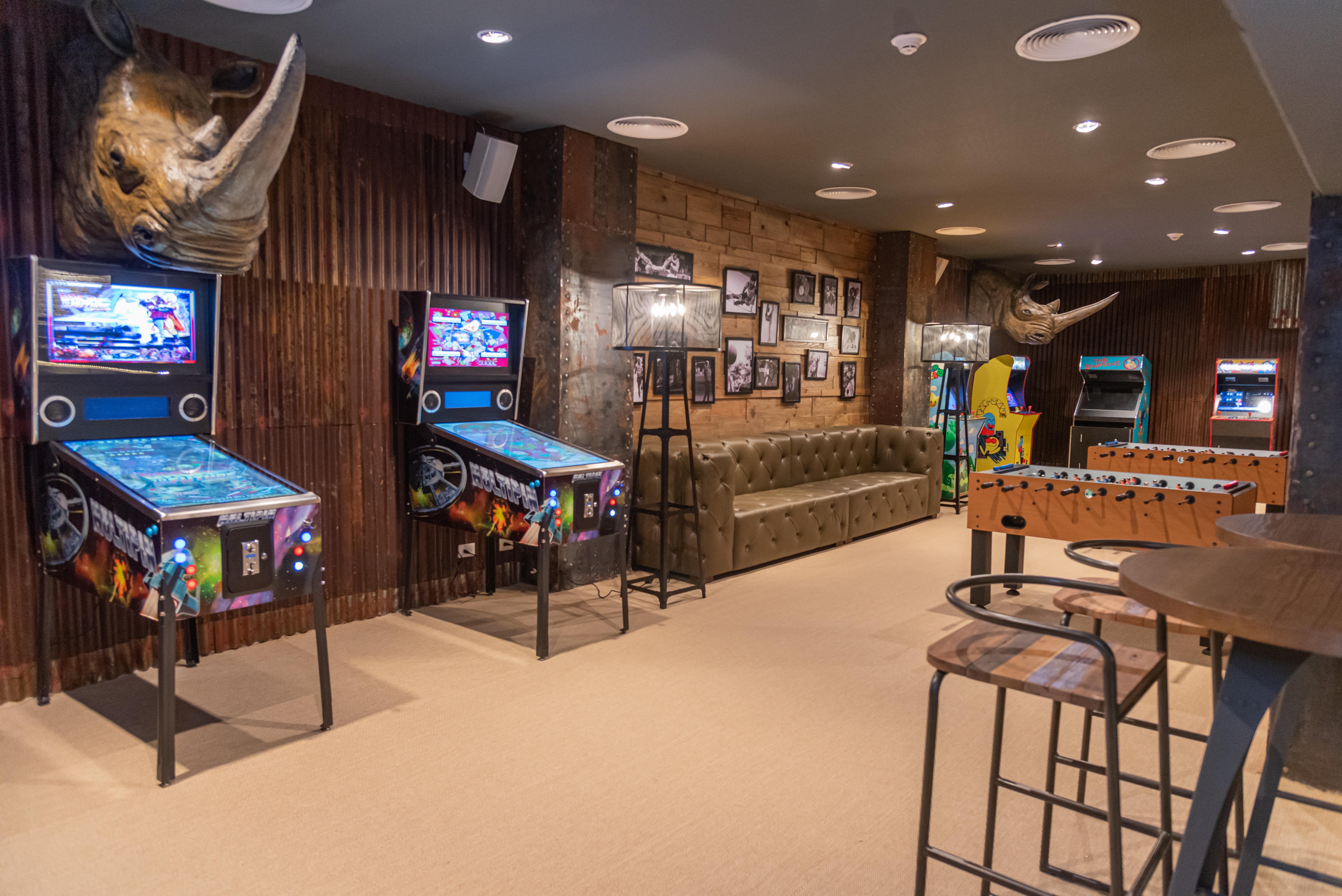 Grand Bavaro Princess All Suites Resort, Spa&Casino Esterno foto The photo shows a game room with a cozy and fun atmosphere. On the left side, there are two pinball machines with colorful graphics. A tufted green sofa is situated against the wall, providing a comfortable seating area. The walls are decorated with 